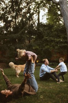 a man and woman playing frisbee with their dog in the park while two other people watch