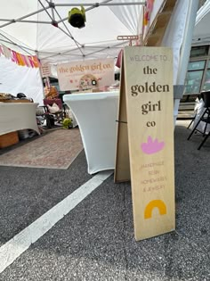 a wooden sign that says welcome to the golden girl co in front of a tent