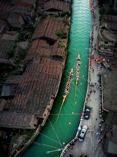 boats are lined up along the river in an aerial view with green water and brown buildings