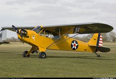 a small yellow airplane sitting on top of a grass covered field next to another plane