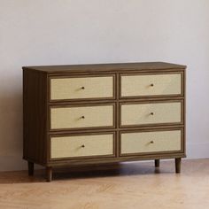 an old dresser with wicker drawers in a white walled room next to a wall