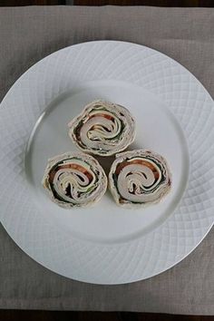 three rolls on a white plate sitting on a table