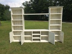 two white bookshelves sitting on top of a lush green field