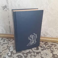 a blue book sitting on top of a table next to a white lace covered wall