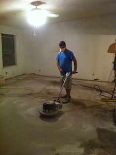 a man is using a floor scruber to clean the concrete in an empty room