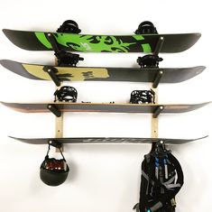 three snowboards mounted to the side of a wall with skis hanging on it