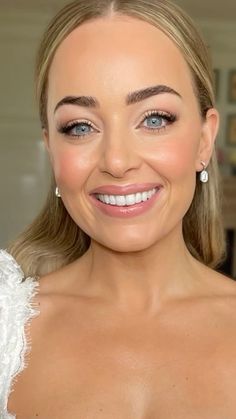 a woman in a white dress smiling at the camera with blue eyes and blonde hair