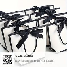 six white gift bags with black ribbon tied around the top and bottom, all lined up together