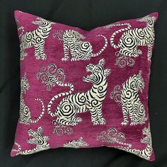 a pink and white decorative pillow with an animal design on the front, sitting on a black background