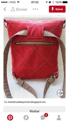 a red handbag with brown straps on it