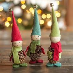 three little gnomes are standing next to each other with pine cones on their feet