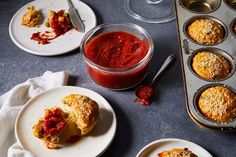 some muffins are on plates next to a cup of sauce and a pan