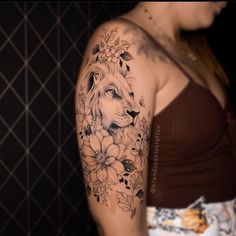 a woman with a lion and flowers tattoo on her arm is standing in front of a wall