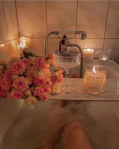 a person's feet in a bathtub with candles and flowers