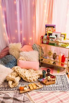 a bed with lots of pillows and blankets on top of it next to a shelf