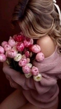 a woman holding a bunch of flowers in her hands