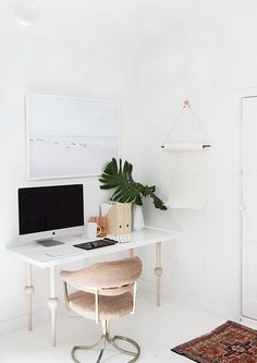 a white desk with a computer on it and a rug in front of the desk