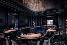 a casino room with tables, chairs and chandelier hanging from the ceiling above