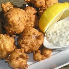 a white plate topped with tater tots next to a lemon wedge and dipping sauce