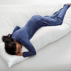 a woman laying on a pillow with her arms behind her back and head resting on the pillow