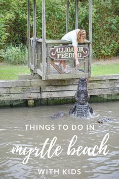 a woman standing on top of a wooden dock next to an alligator in the water