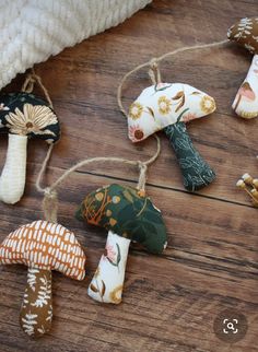 small mushrooms are hanging from twine strings on a wooden floor with white blanket and pillow in the background