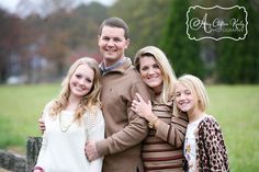 a family posing for a photo in front of a fence