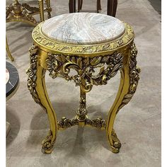 an ornately decorated table with marble top and gold trimmings on the legs