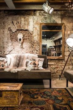 a living room filled with furniture and a brick wall behind the couch is a large mirror