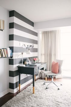 a black and white striped wall in an office with a desk, chair, and bookshelf