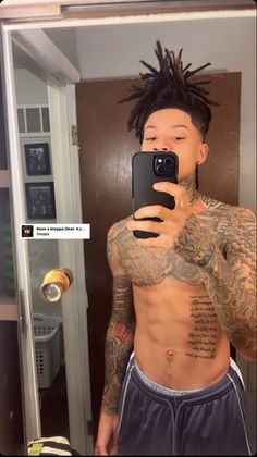 a man with dreadlocks taking a selfie in the mirror while wearing shorts