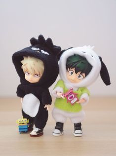 two toy figurines are standing next to each other on a wooden table and one is wearing a black bunny costume