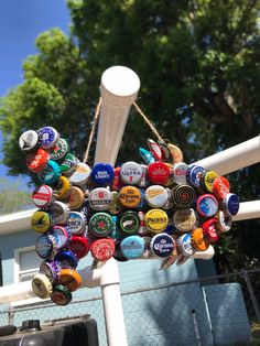 an umbrella made out of beer bottle caps hanging from a chain on the side of a fence