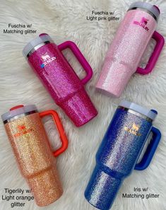 three different colored mugs sitting next to each other on a white fur covered surface