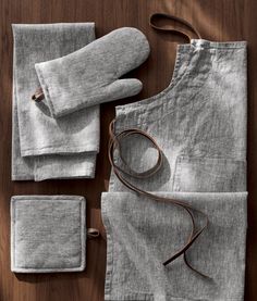 an apron, gloves and napkins are laid out on a wooden table with a brown cord