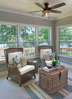 a living room with two wicker chairs and a coffee table in front of large windows