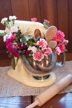 a metal bowl with flowers and spoons in it