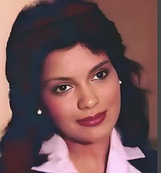 a close up of a person wearing a white shirt and black blazer with her hair pulled back