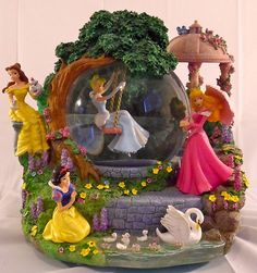 the snow globe has princess figurines in it and is surrounded by other disney characters