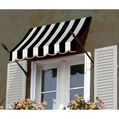 a black and white striped awning over a window with flowers in the foreground