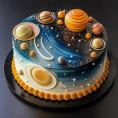 a cake decorated with solar system on top of a black plate and gold trimmings