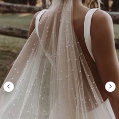 the back of a woman's wedding dress with white pearls on it and an appliqued veil