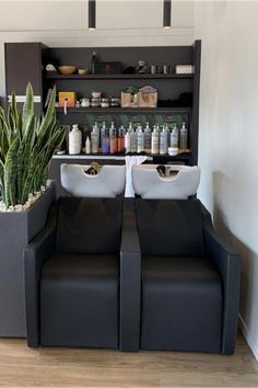 two black couches sitting next to each other in front of a shelf with bottles on it