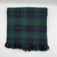 a green and black plaid blanket laying on top of a white surface