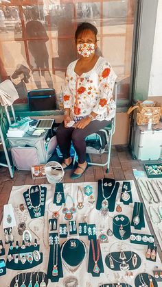 a woman sitting on a chair surrounded by various necklaces and bracelets, with her face painted