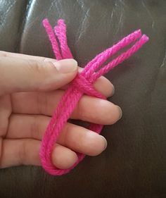 a hand holding a pink rope on top of a leather couch