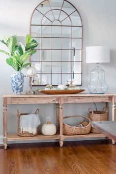 a console table with baskets on it and a mirror behind it in a living room