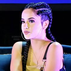 a woman with braids sitting on a blue couch in front of a tv screen