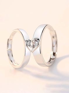 two white gold wedding rings with heart shaped diamond in the middle, set on top of each other