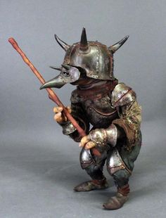 a statue of a man in armor holding a stick and wearing a helmet with horns